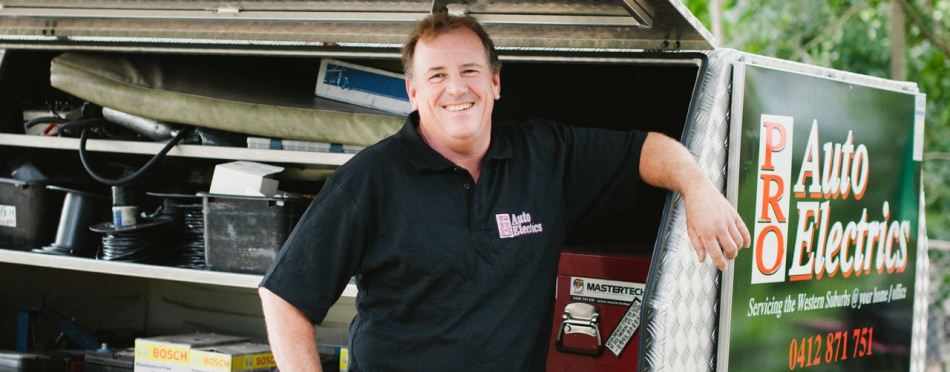 Brett Baxter leaning on his Pro Auto Electrics service van, tools and parts on the shelves behind him