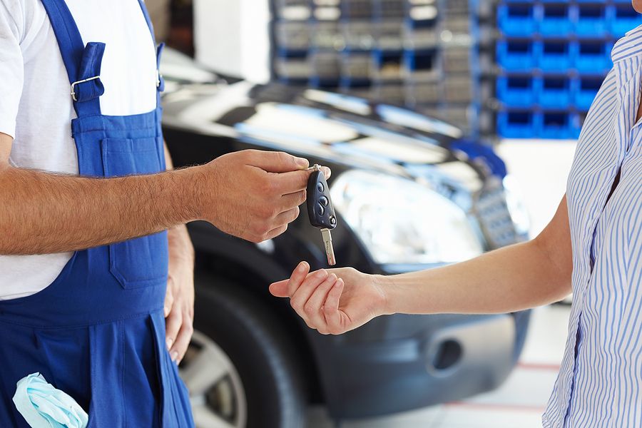 Car keys being handed over in front of a car